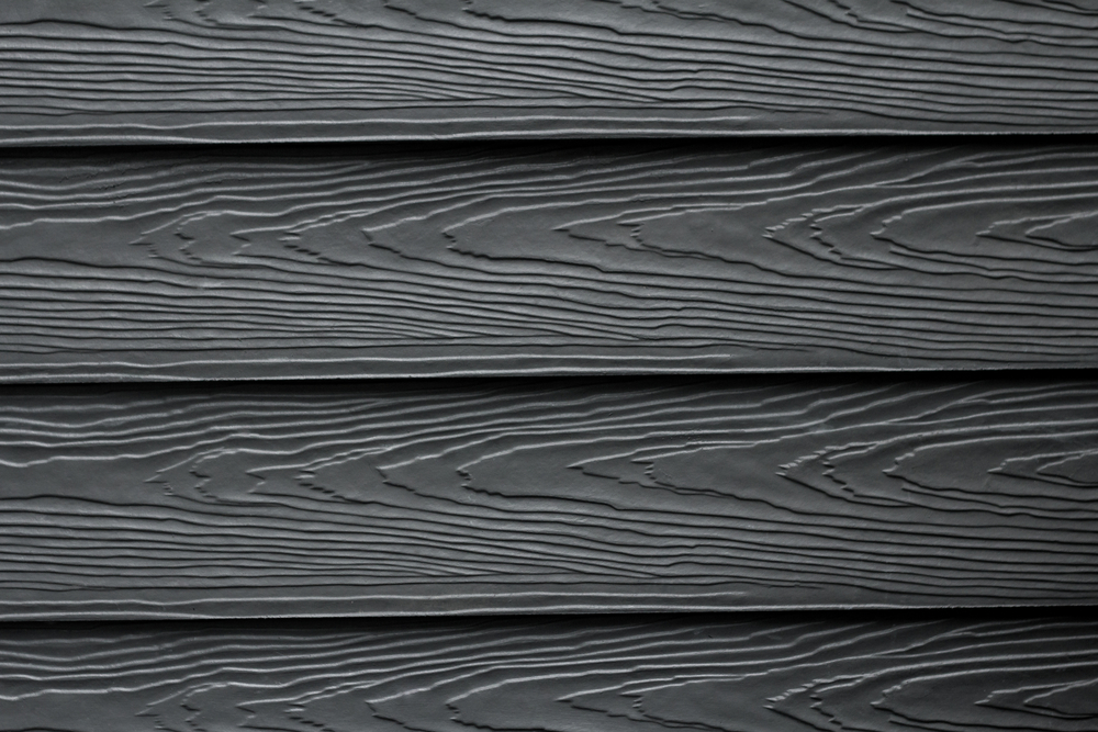 A close up of four panels of black fiber-cement siding.